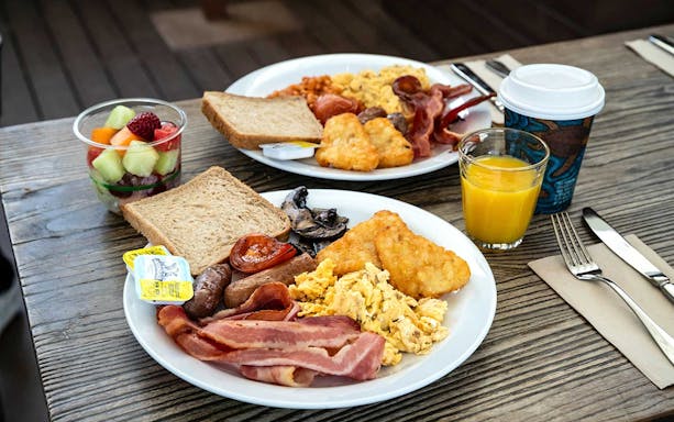 Breakfast spread with scrambled eggs, bacon, toast, and fruit at WILD LIFE Sydney Zoo.