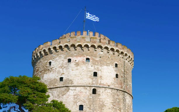White Tower with Greek flag in Thessaloniki, Greece.
