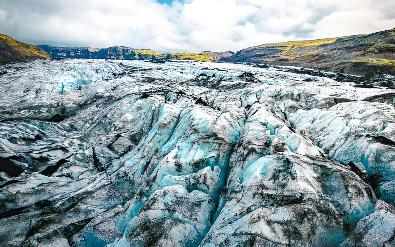 Sólheimajökull Glacier with ice formations and distant hills in Iceland.
