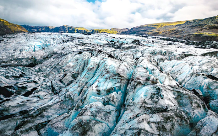 Sólheimajökull Glacier with ice formations and distant hills in Iceland.