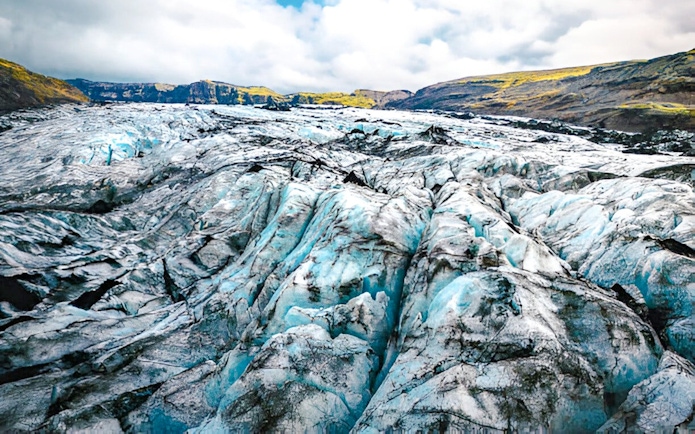 Sólheimajökull Glacier with ice formations and distant hills in Iceland.