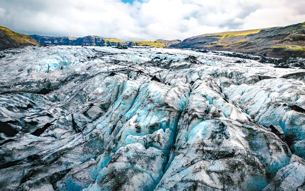 Sólheimajökull Glacier with ice formations and distant hills in Iceland.
