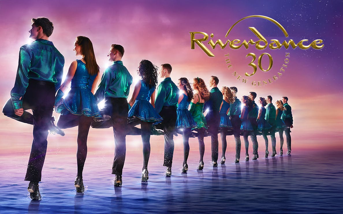 Dancers performing Riverdance against a sunset backdrop.