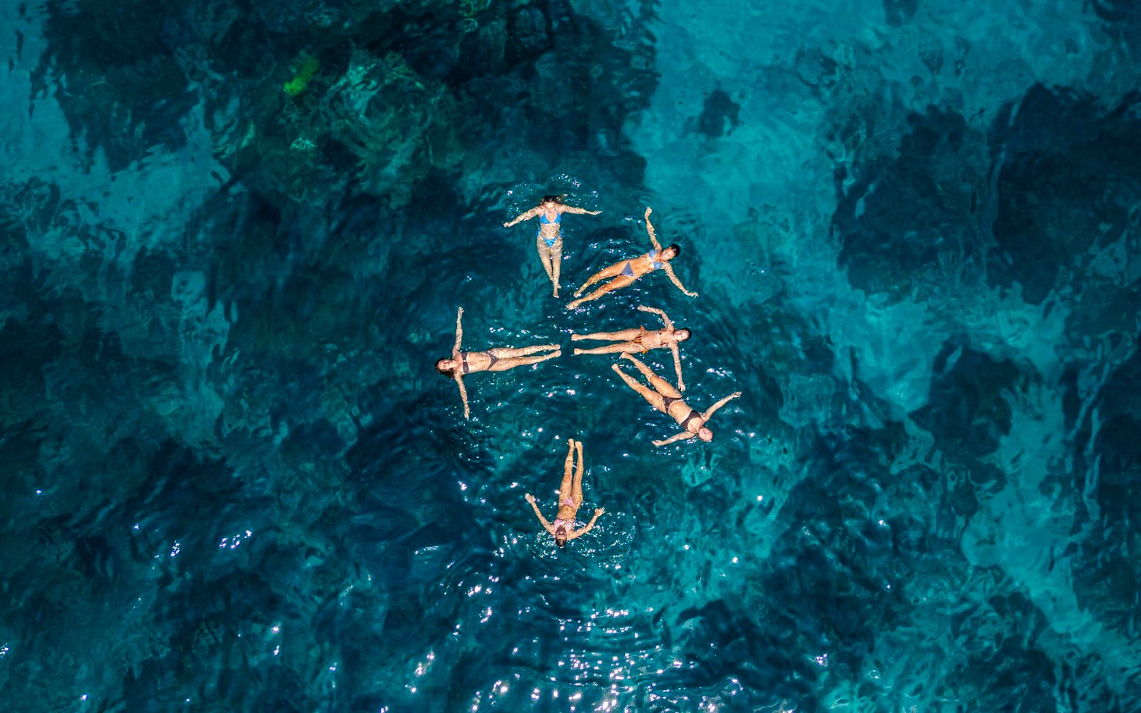 People floating in clear blue water during West Nusa Penida Island Tour.