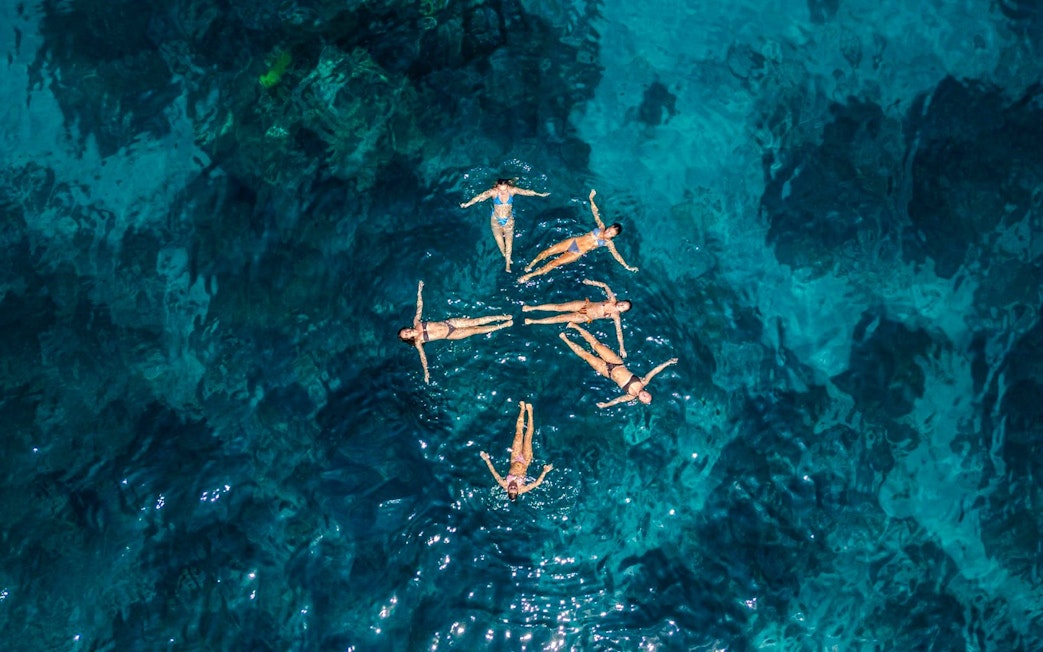 People floating in clear blue water during West Nusa Penida Island Tour.