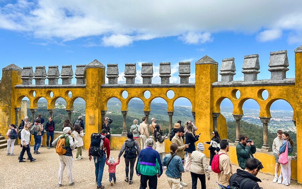 Tourists exploring the terrace of Pena Palace with scenic views in Sintra, Portugal.