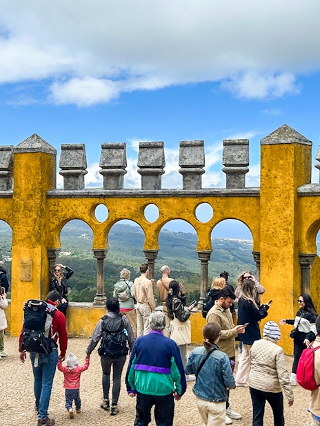 Tourists exploring the terrace of Pena Palace with scenic views in Sintra, Portugal.