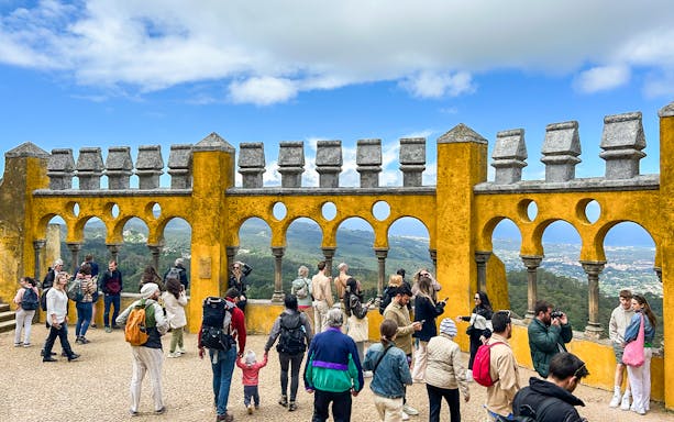 Tourists exploring the terrace of Pena Palace with scenic views in Sintra, Portugal.