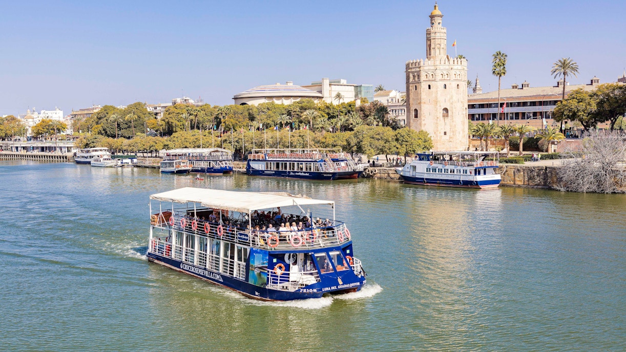 Cruise boat on Guadalquivir River passing Torre del Oro in Seville.