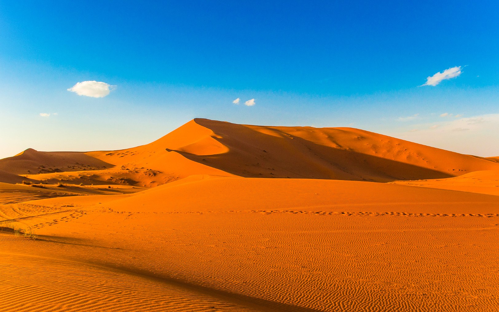 Merzouga sand dunes under clear blue sky, Morocco.