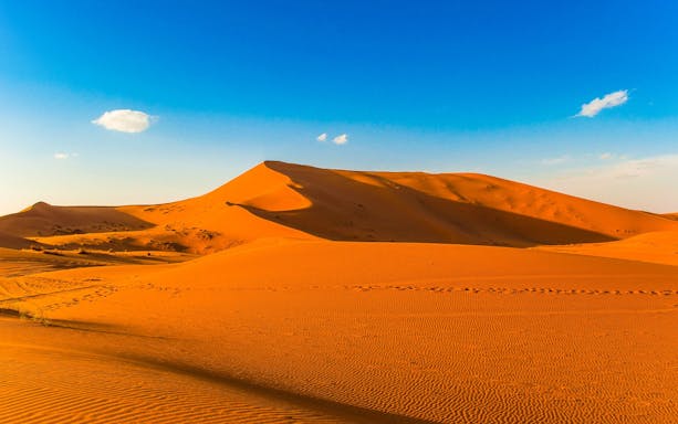 Merzouga sand dunes under clear blue sky, Morocco.