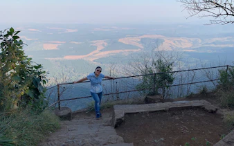 Person standing on a viewpoint overlooking the Panorama Route landscape in South Africa.