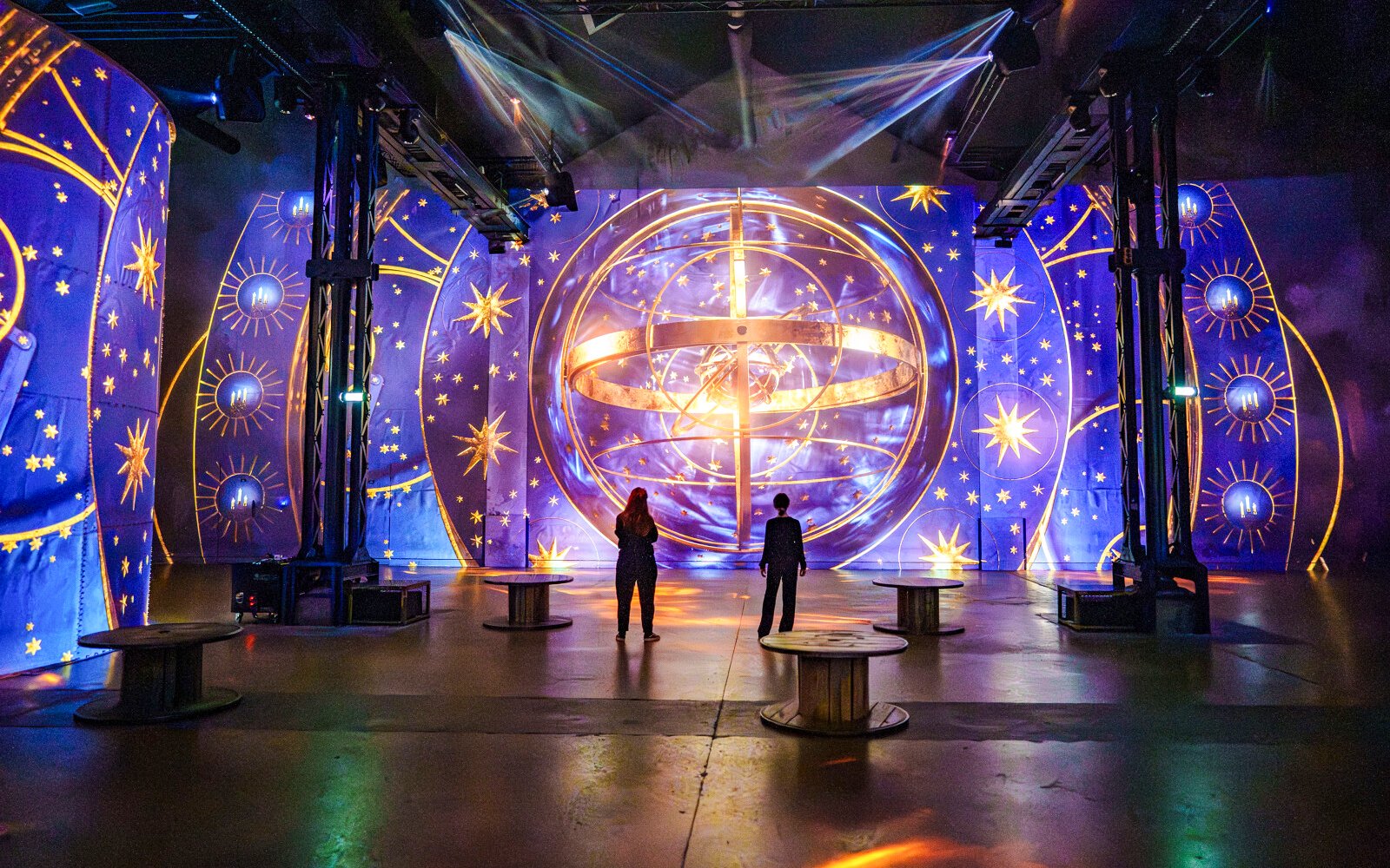 Visitors at RENAISSANCE immersive experience, Atelier des Lumières, Paris, with celestial projections.