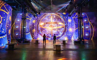 Visitors at RENAISSANCE immersive experience, Atelier des Lumières, Paris, with celestial projections.