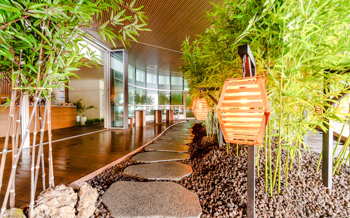 Stone pathway with glowing lanterns and bamboo decor in Club D Oasis spa area.