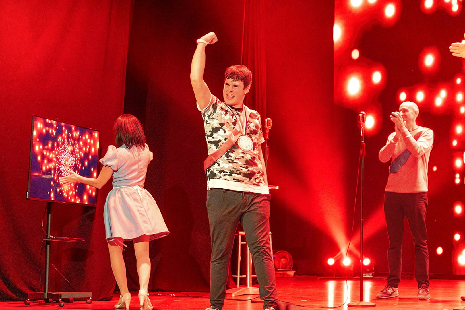 Performers on stage during "Coctel, un Musical al revés" with vibrant red lighting.