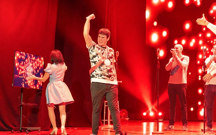 Performers on stage during "Coctel, un Musical al revés" with vibrant red lighting.