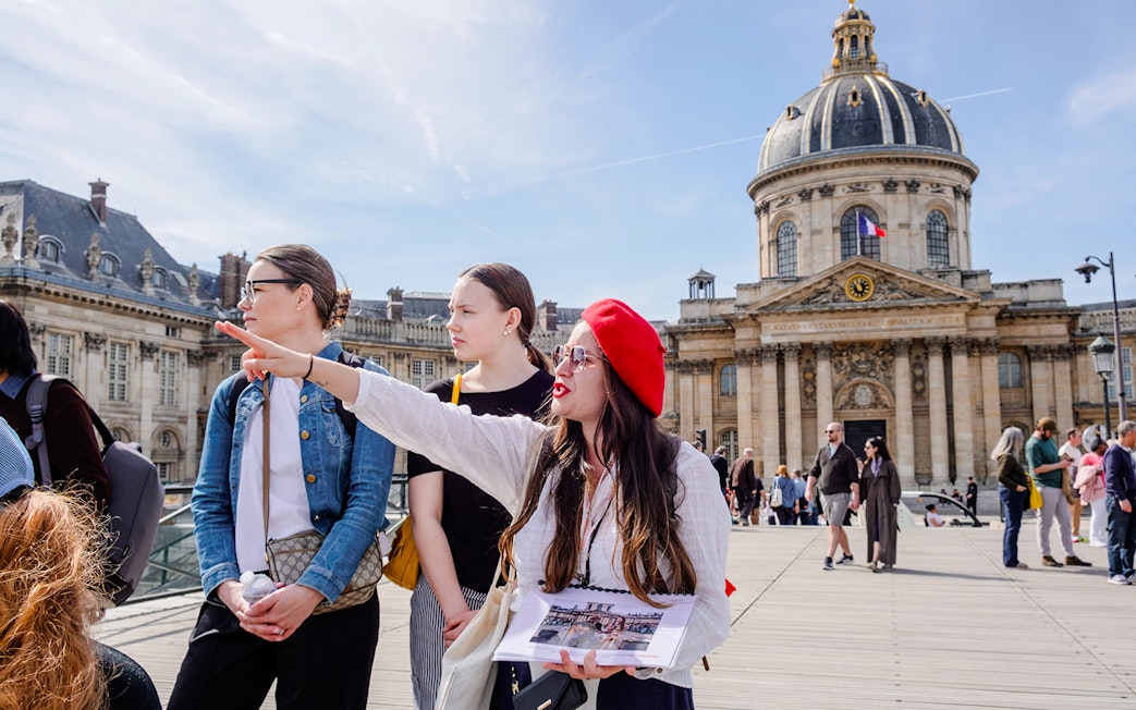 Guide leading tourists on Emily in Paris Locations Walking Tour near historic Parisian building.