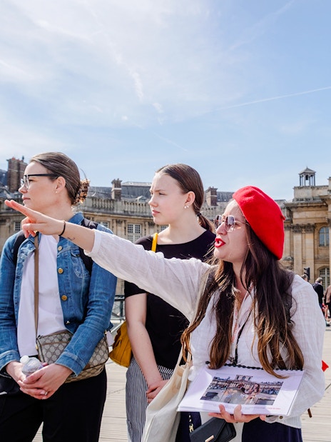 Guide leading tourists on Emily in Paris Locations Walking Tour near historic Parisian building.