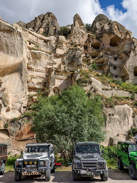 Jeep safari vehicles parked in front of Cappadocia rock formations, Turkey.