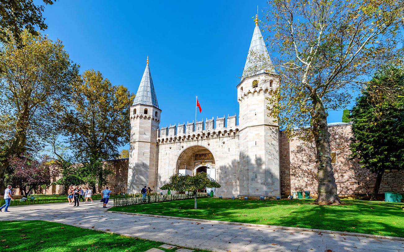 Gate of Salutation at Topkapi Palace, Istanbul, with visitors walking nearby.