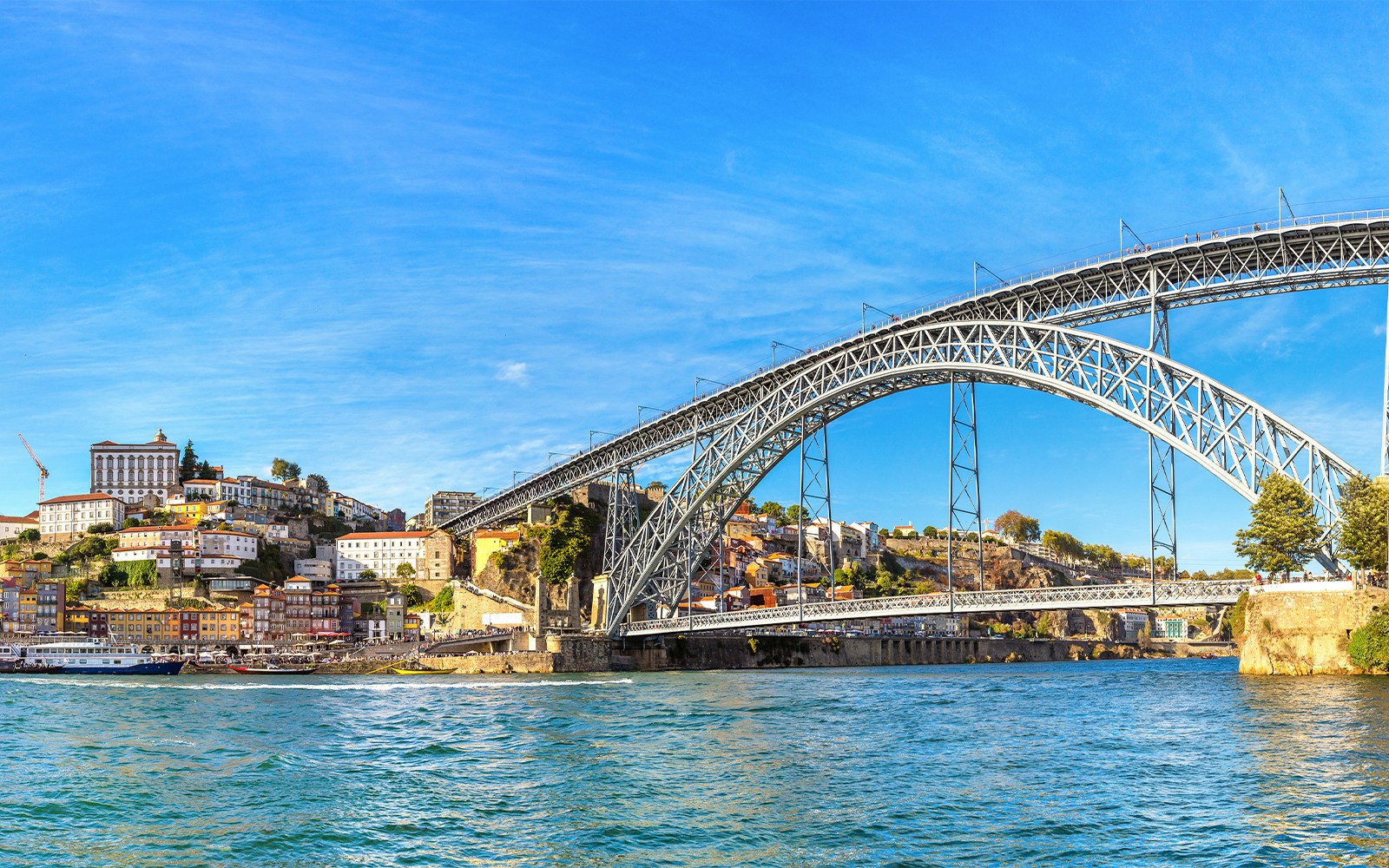 Dom Luis Bridge spanning the Douro River in Porto, Portugal, with colorful hillside buildings.
