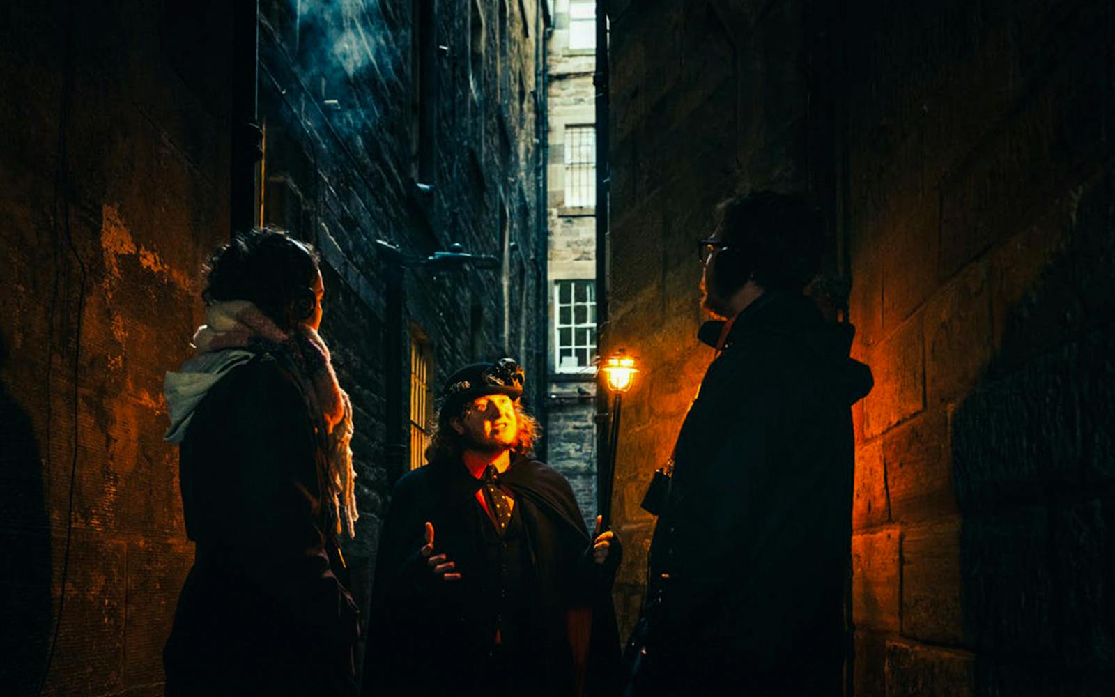 Guests on a guided tour in a dimly lit Edinburgh alleyway.