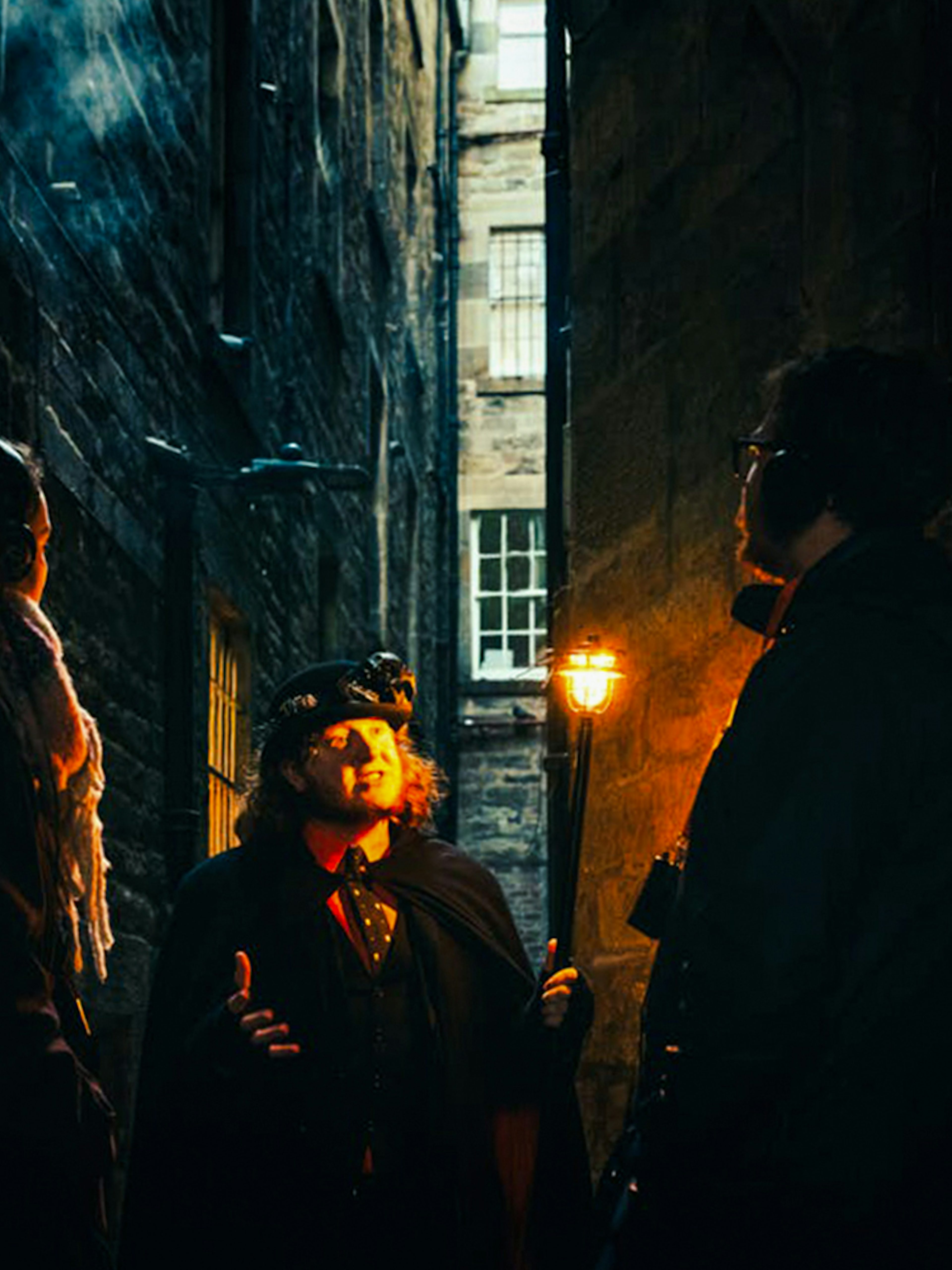 Guests on a guided tour in a dimly lit Edinburgh alleyway.