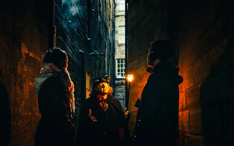Guests on a guided tour in a dimly lit Edinburgh alleyway.