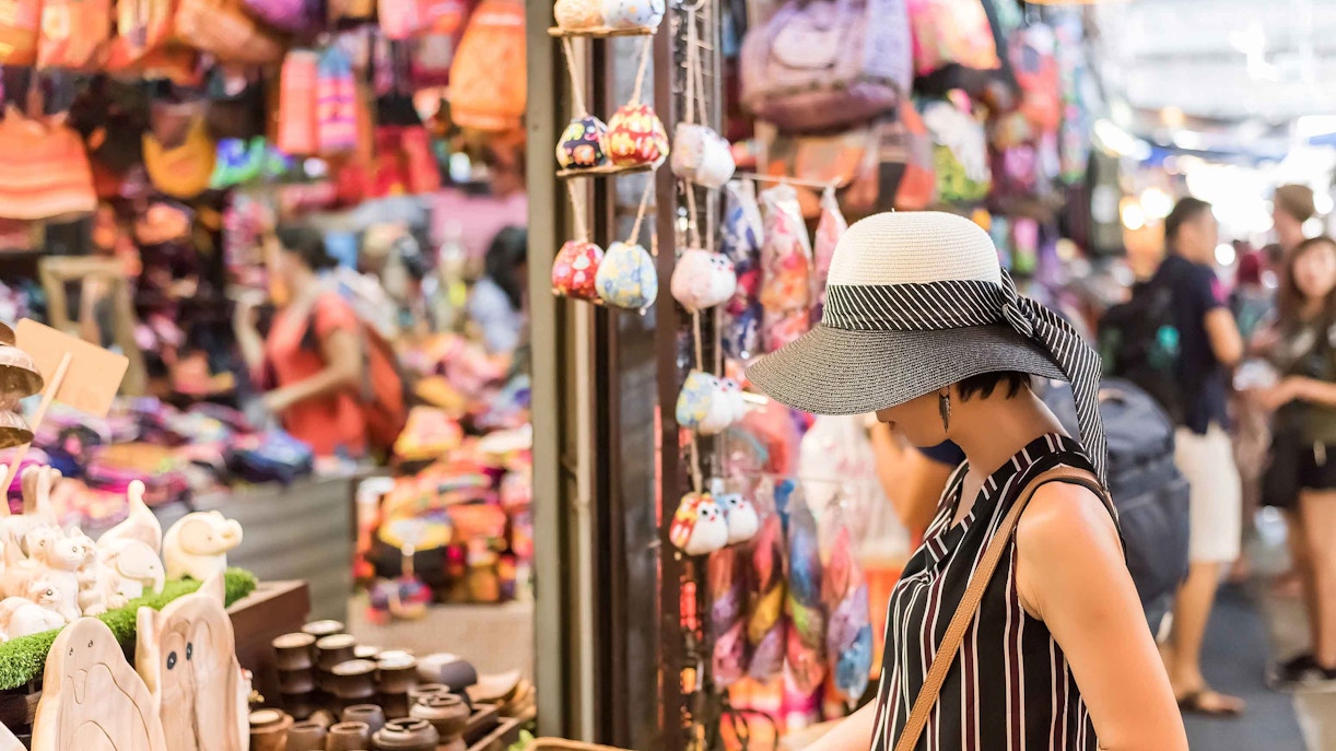 Shopper browsing handmade crafts at Chatuchak Weekend Market, Bangkok.