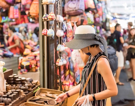 Shopper browsing handmade crafts at Chatuchak Weekend Market, Bangkok.