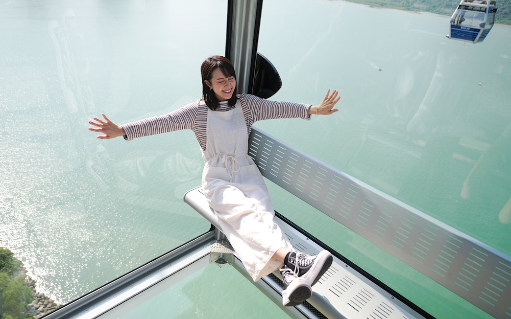 Person enjoying a ride in the Ngong Ping Cable Car over water in Hong Kong.