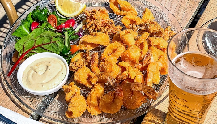 Crispy calamari and beer served at an outdoor cafe table