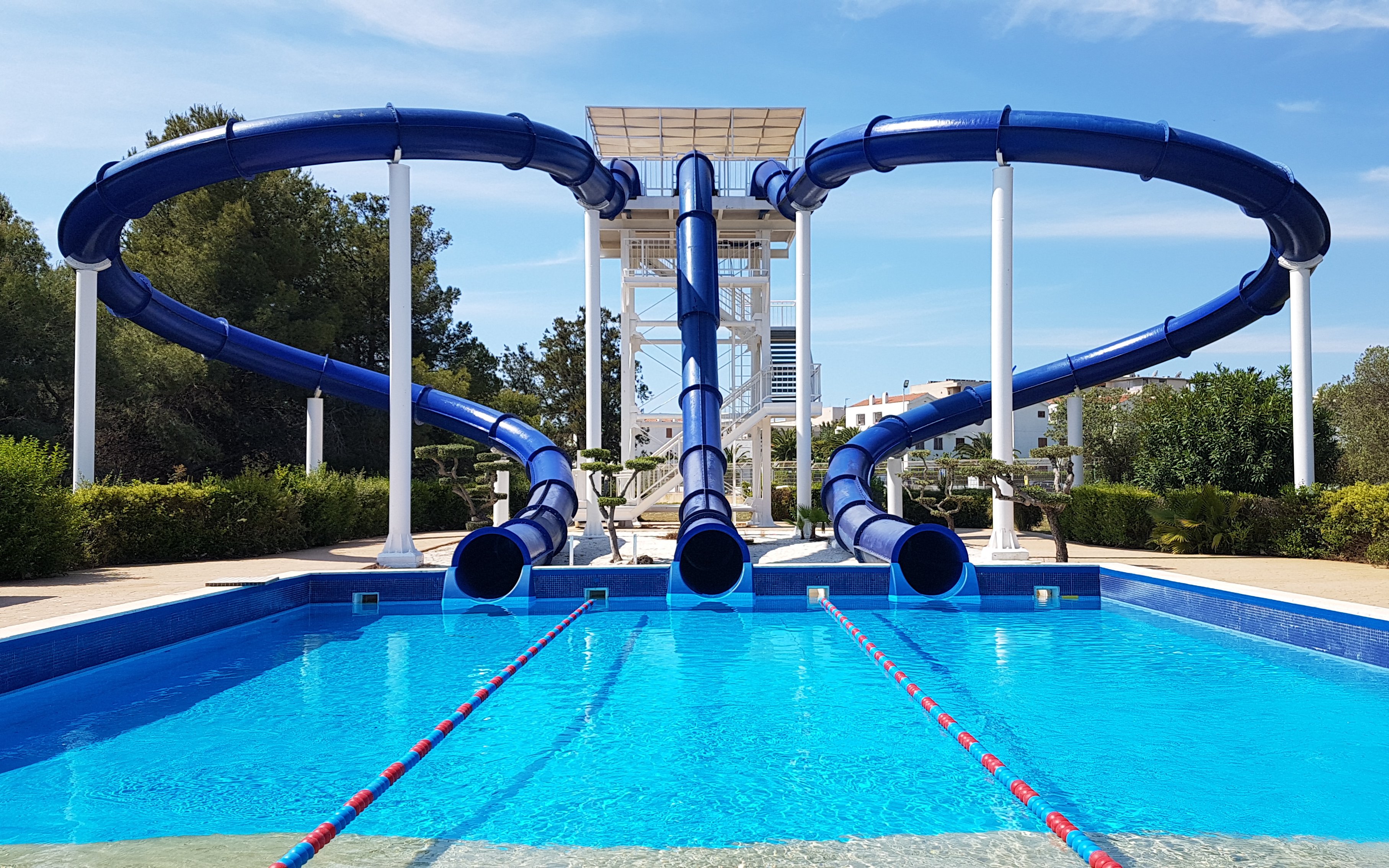 Water slides at Aquopolis Costa Daurada in Tarragona, leading into a clear blue pool.