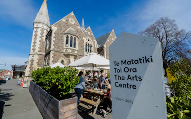 Christchurch Arts Centre courtyard with visitors enjoying coffee under umbrellas.