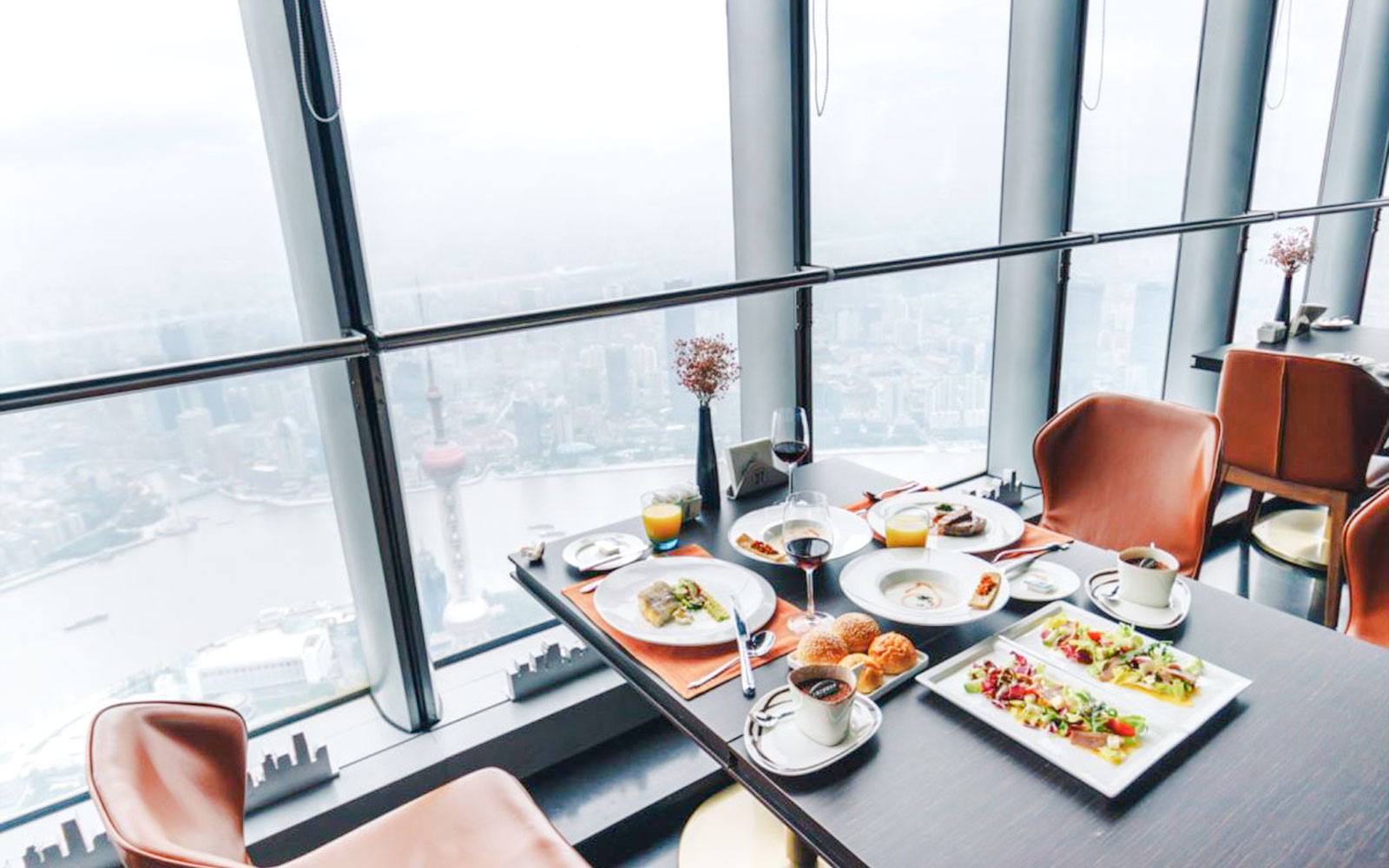 Dining table with meals and drinks overlooking Shanghai skyline from Shanghai Tower restaurant.