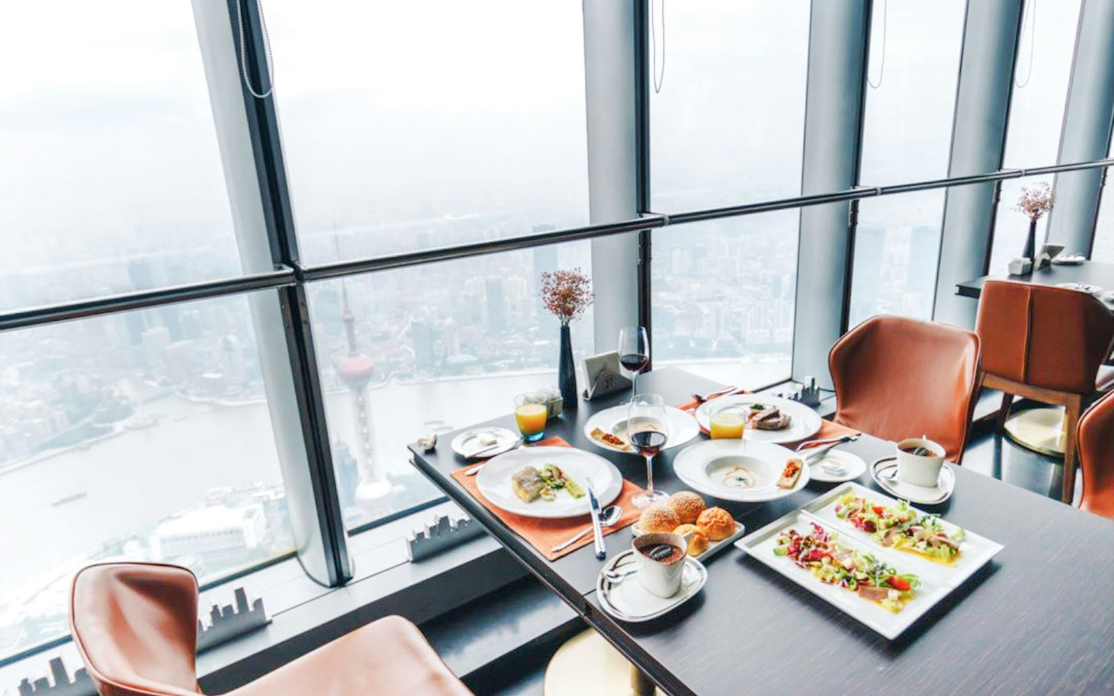 Dining table with meals and drinks overlooking Shanghai skyline from Shanghai Tower restaurant.