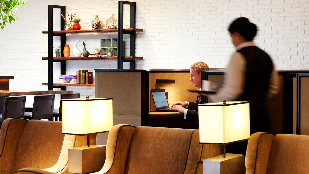 Plaza Premium Lounge seating area with guest working on laptop, Terminal 4, London Heathrow Airport.