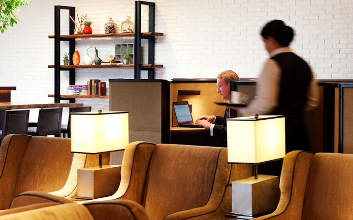 Plaza Premium Lounge seating area with guest working on laptop, Terminal 4, London Heathrow Airport.