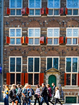Rembrandt House Museum facade with visitors walking, Amsterdam.