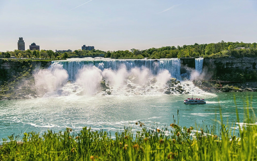 Boat approaching Niagara Falls with mist rising, part of Exclusive Access Boat Ride & Journey Behind the Falls.