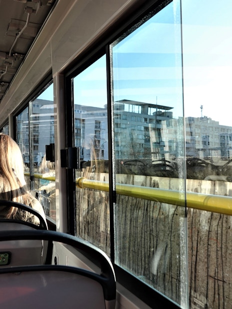 Passengers on Berlin hop-on hop-off bus tour viewing cityscape through windows.