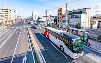 Kansai Airport shared shuttle van driving on a sunny day in an urban area.