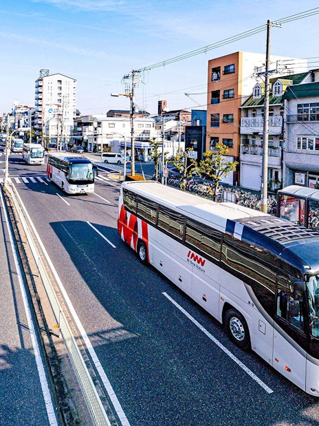Kansai Airport shared shuttle van driving on a sunny day in an urban area.