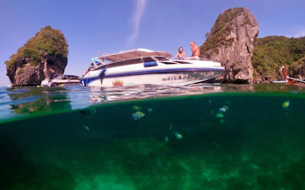 Speedboat near limestone cliffs with tropical fish in Krabi, Thailand.