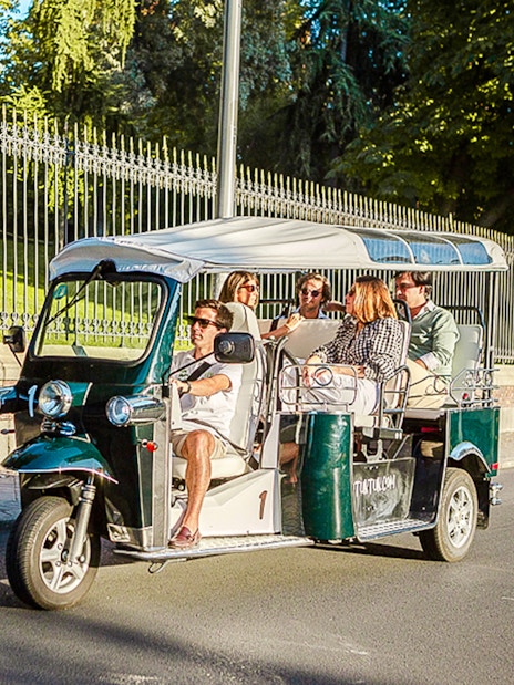 Tourists enjoying a private eco tuk-tuk ride in Madrid.