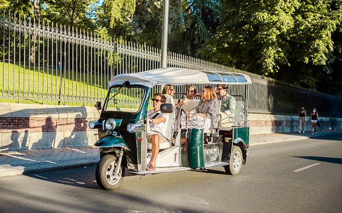 Tourists enjoying a private eco tuk-tuk ride in Madrid.