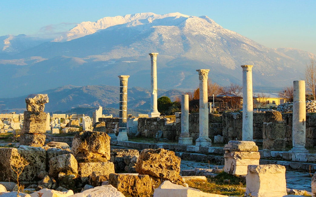 Ancient ruins with stone columns and mountain backdrop in Pompeii, Italy.