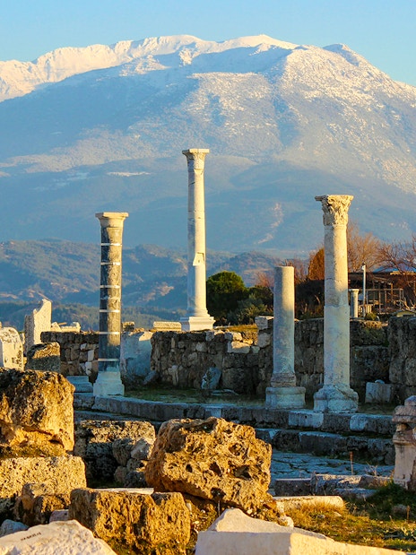 Ancient ruins with stone columns and mountain backdrop in Pompeii, Italy.