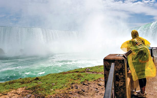 Woman in yellow poncho viewing Niagara Falls from observation point.